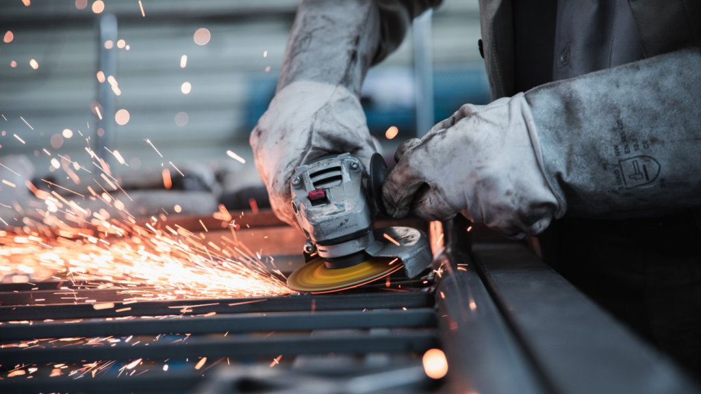 a factory worker using an angle grinder on steel gate