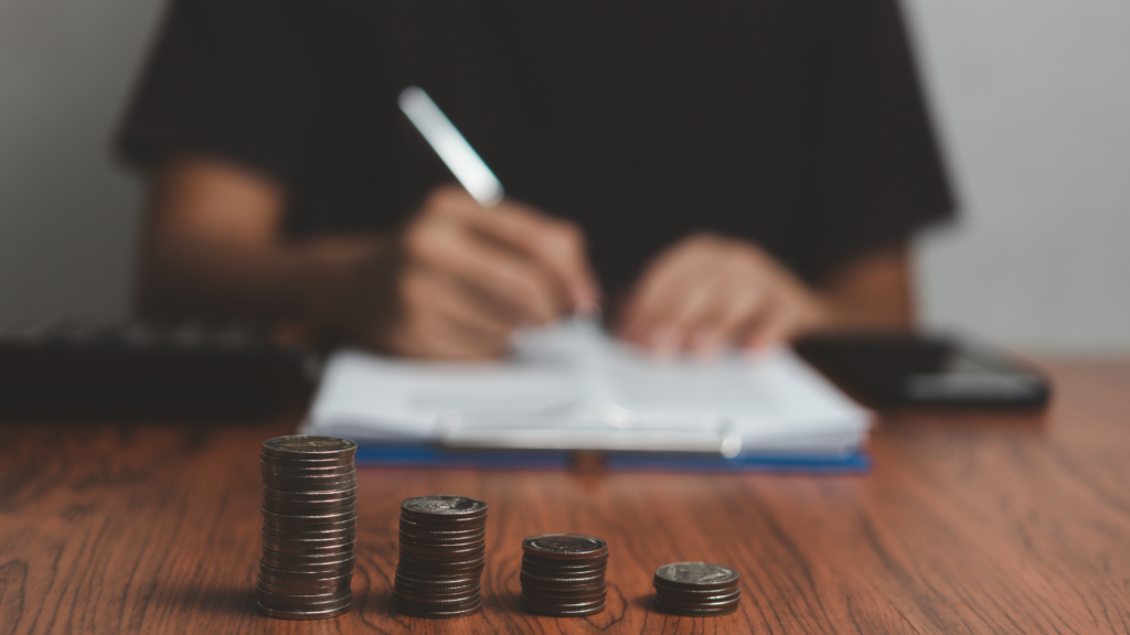 a person writing notes with stacks of coins in front of them