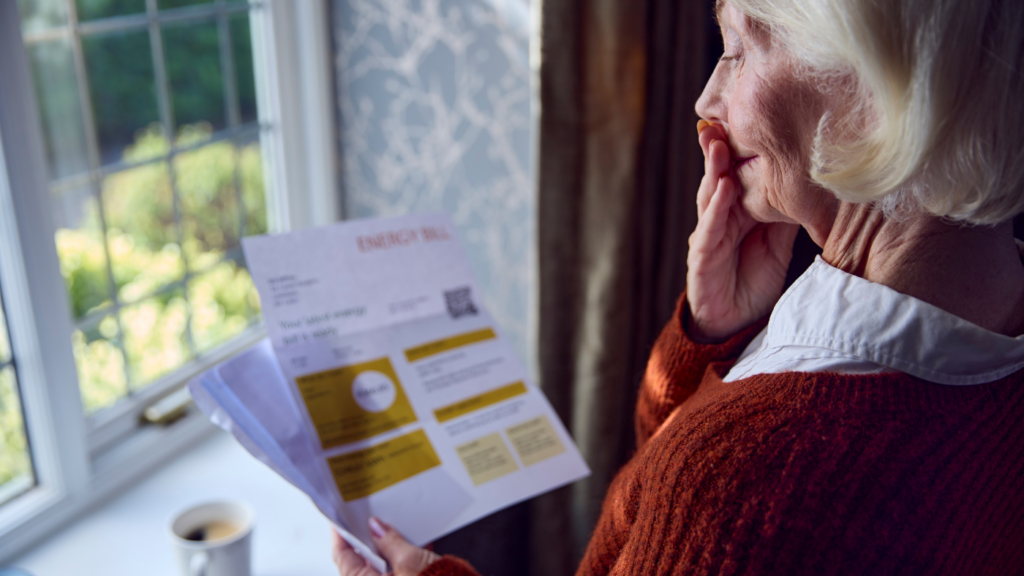 a woman holding a bill and holding a hand to her mouth as if she were in shock