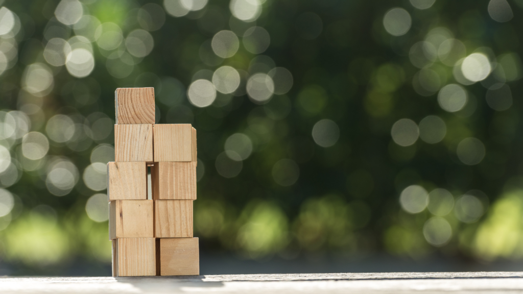 A stack of wooden cubes in front of green forest background