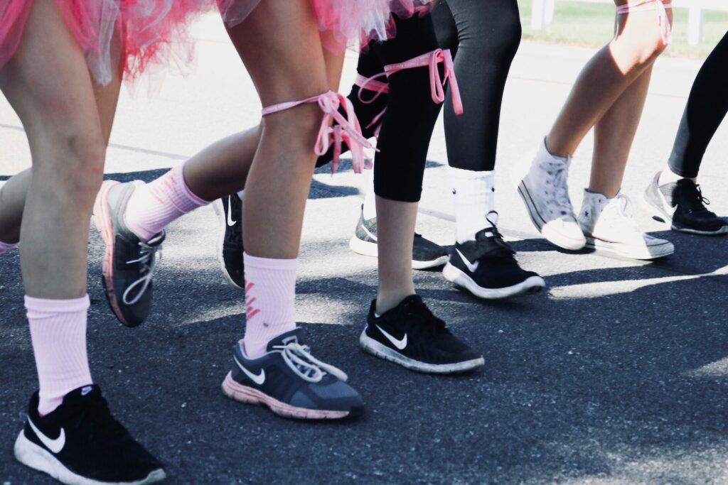 Legs of female runners with pink socks and ribbons.