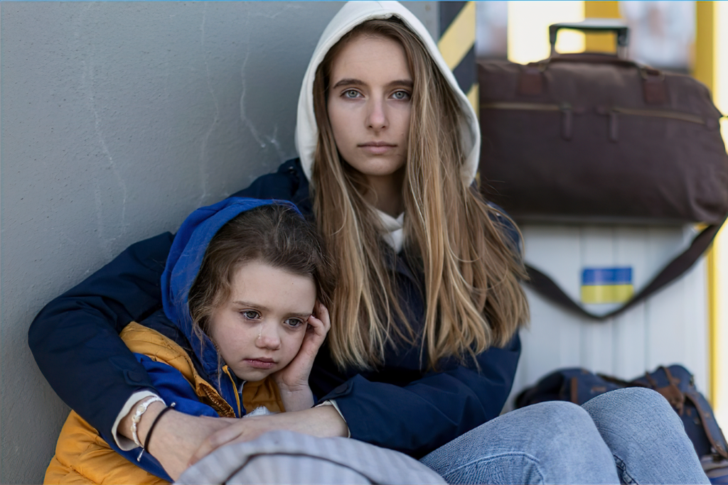 Two sisters, one about 15, the other one about 8 years old, hugging.