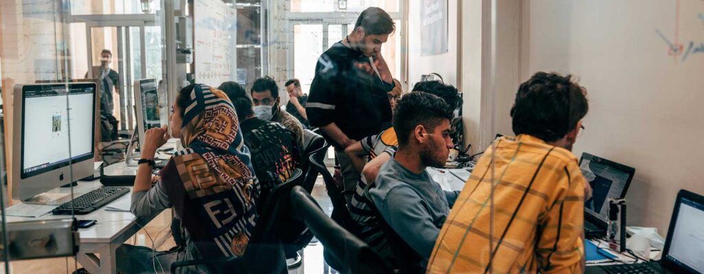 Women and men in a room with computers, filling out asylum seeking documents.