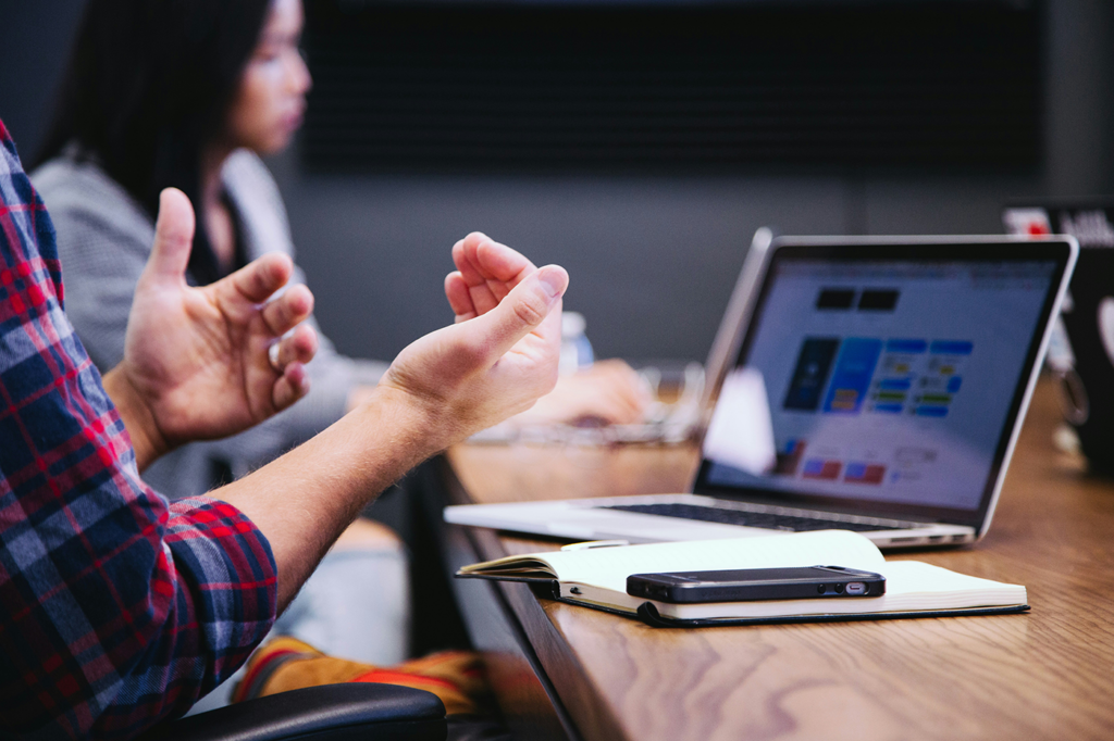 Man's hands in front of a laptop gesticulating a point to emphasize on something he is saying.