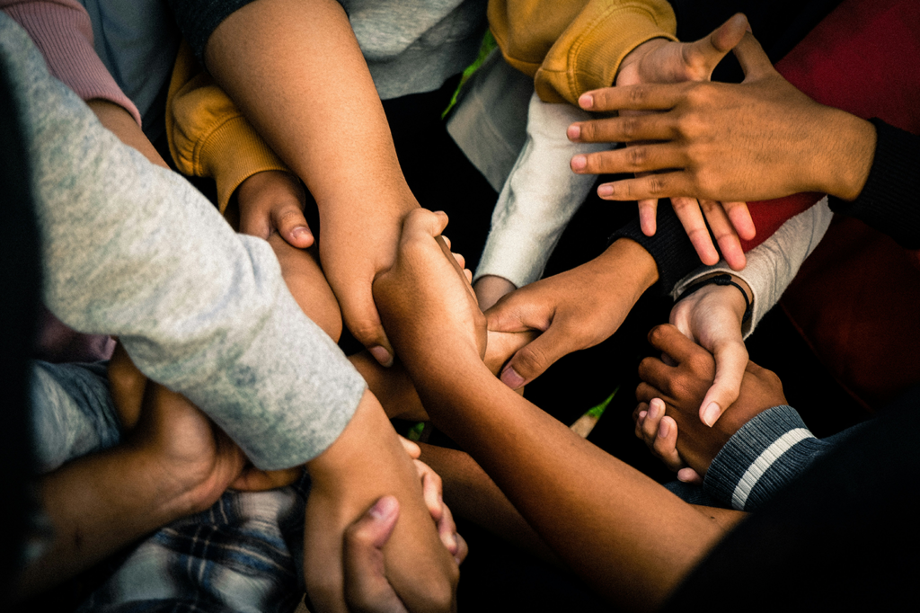 Many hands shaking hands over and under each other.