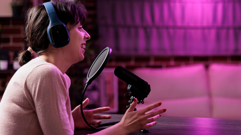 A woman wearing headphones speaks into a microphone while participating in a podcast