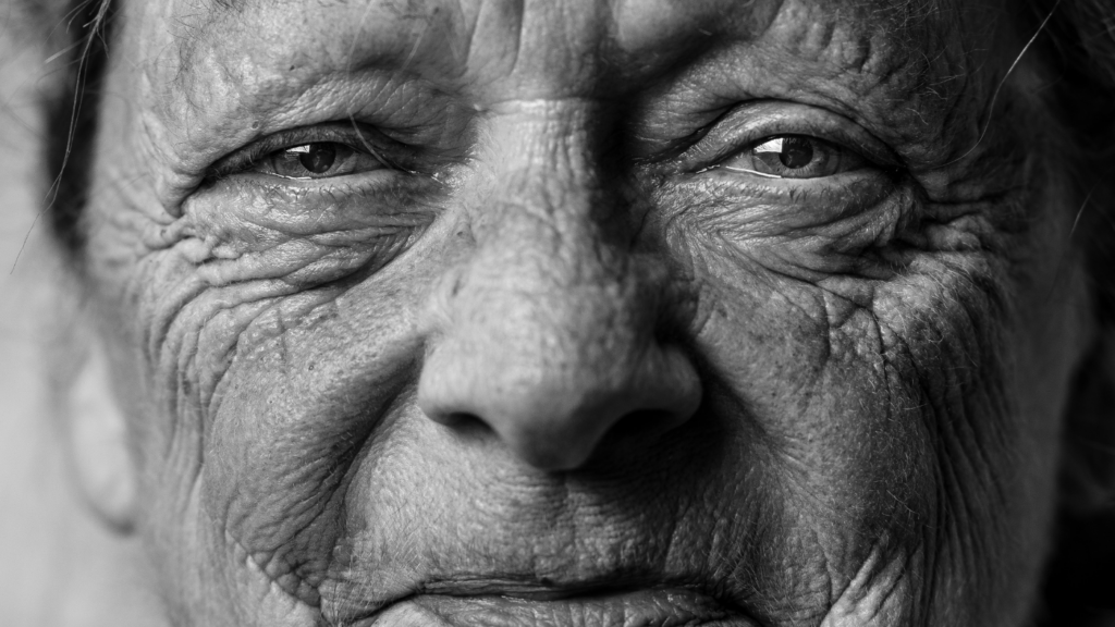 A face of a smiling older lady in black and white.