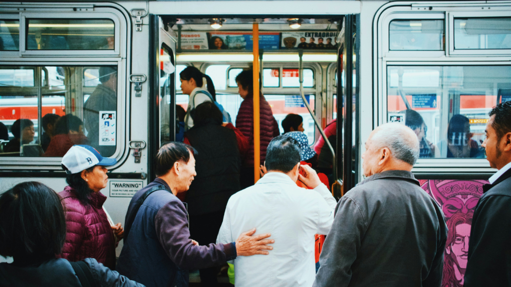 an elderly man in a white coat is helped onto a bus by middle-aged man