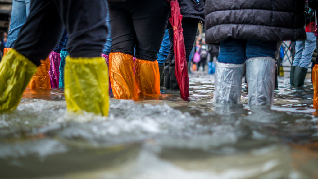 A group of people in waterproof boots standing in a flooded street.