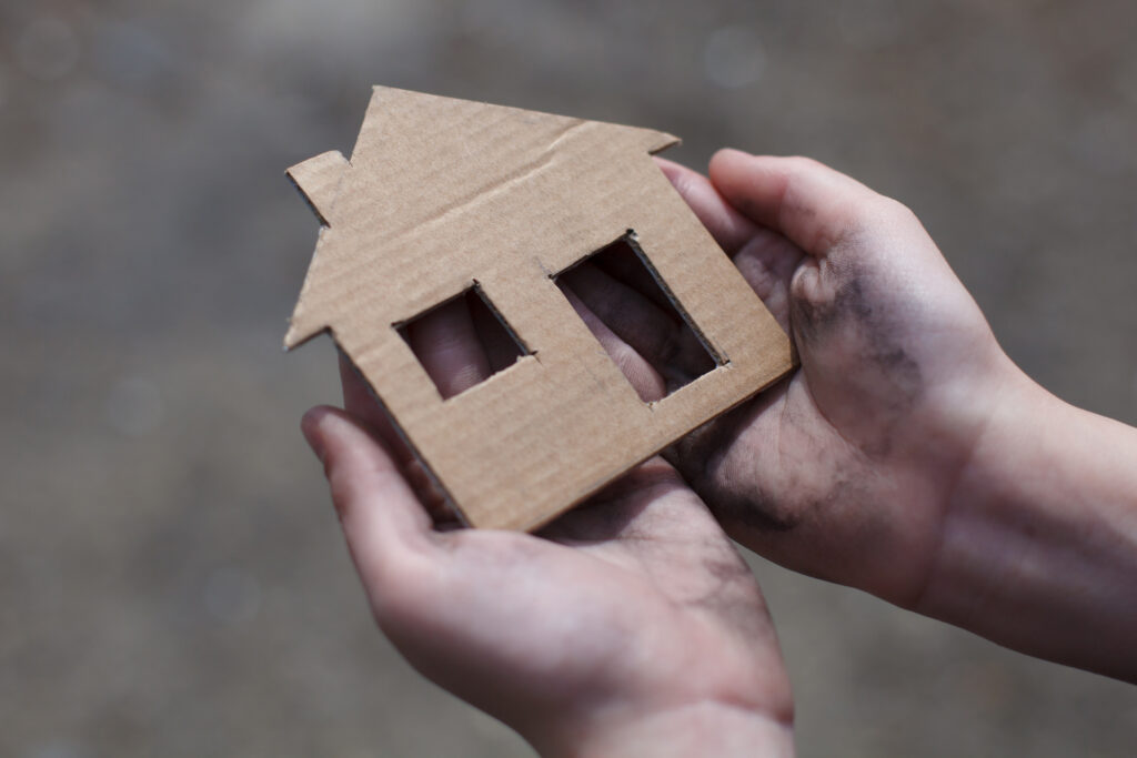 homeless boy holding a cardboard house, dirty hand