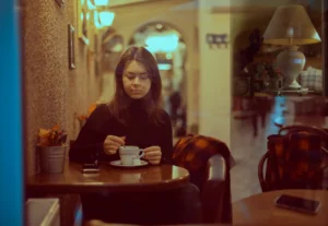 a young woman from Ukraine sits in a coffee shop in a pensive mood 